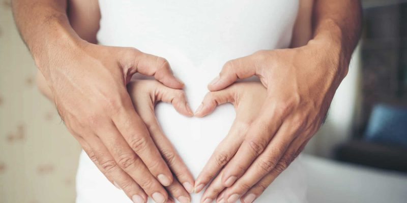 pregnant-woman-her-husband-hand-showing-heart-shape-1-1